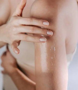 Close-up of a person's arm with a hand gently touching the skin, showing smooth skin texture.